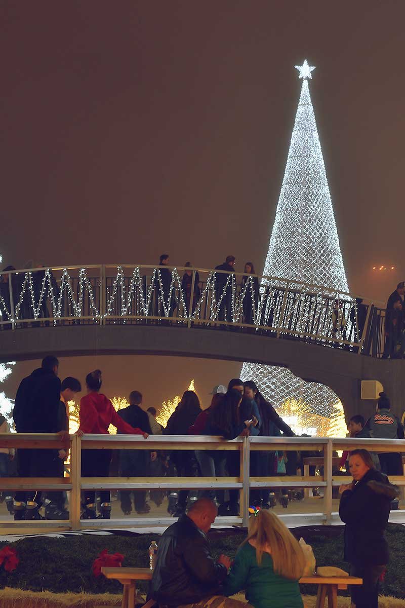  visitors playing outdoor ice skates at Enchant Arlington Texas during holiday season